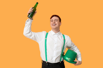 Wall Mural - Happy young man with leprechaun's hat and bottle of beer on yellow background. St. Patrick's Day celebration