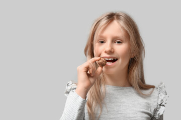 Sticker - Cute little girl with sweet chocolate candy on grey background