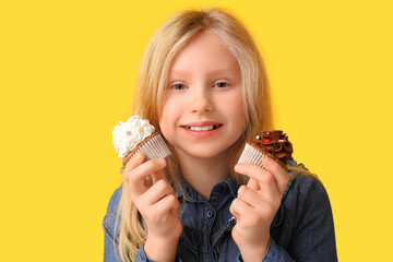 Canvas Print - Cute little girl holding cupcakes on yellow background