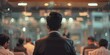© huiying - Confident businessman in sweater vest giving a professional presentation to attentive colleagues in a modern glass-walled office. Corporate meeting and teamwork concepts.