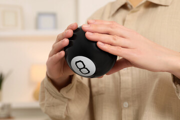 Wall Mural - Woman holding magic eight ball indoors, closeup