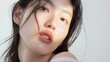 © TGIF - Beautiful Korean model in 20s with innocent image, mid-shot against white background, showcasing cool sensation on dewy skin while applying serum.