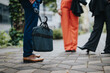 © qunica.com - Group of business professionals standing outdoors on a city street carrying a briefcase and umbrellas. Cropped photo.