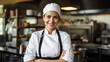 © Xyeppup - Smiling female chef in uniform, bright natural light, close-up, professional kitchen setting.