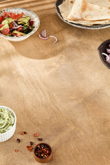 Wall Mural - Rustic Wooden Table Setup with Fresh Vegetable Salad, Lavash Bread, Onion, and Spices in Warm Daylight