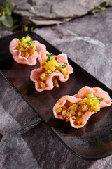 Wall Mural - Salmon Tartare in Rice Chips Garnished with Fresh Herbs and Mango Salsa on Dark Slate Plate