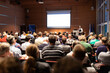 © kasto - Speaker giving a talk in conference hall at business meeting event. Rear view of unrecognizable people in audience at the conference hall. Business and entrepreneurship concept.