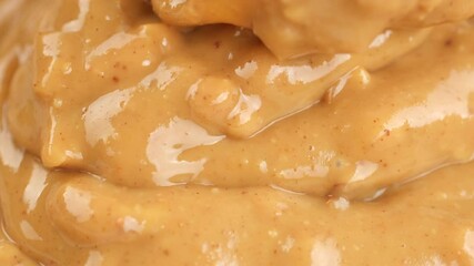 Wall Mural - Pouring crunchy peanut butter with pieces of peanuts in bowl, close up