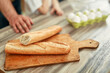 © Valerii Apetroaiei - Freshly baked French bread on a wooden cutting board, set in a kitchen atmosphere