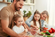 © Valerii Apetroaiei - The family is joyfully cooking together in a welllit kitchen using fresh ingredients