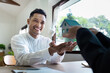 © itchaznong - Real Estate Agent Handing Over House Model to Smiling Client in Bright Office Setting