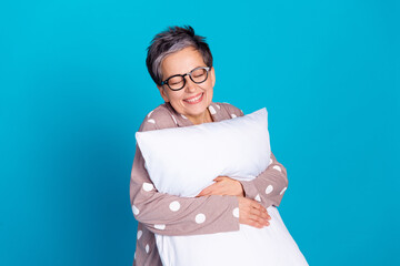 Sticker - Photo of good mood pretty lovely senior woman wear trendy pajama hold soft pillow isolated on blue color background