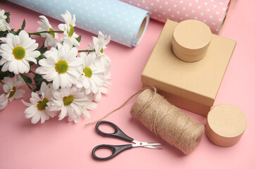 Sticker - Wrapping paper with flowers and a box, a skein of thread and scissors on a pink background. Flat lay