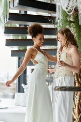 Wall Mural - Two brides in white dresses share a laugh during their wedding reception.