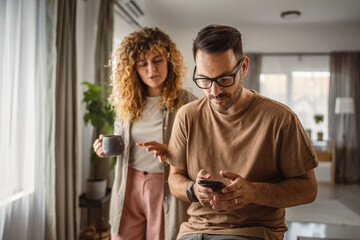 Wall Mural - Husband want to use mobile phone alone while his wife try to join him