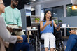 © Wavebreak Media - Leading discussion, woman in wheelchair holding tablet in office meeting
