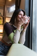 © BUDDHA - Happy young woman enjoying morning coffee drink and smiling indoors cafeteria. Relaxing, taking a break.