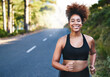 © peopleimages.com - Happy woman, portrait and running with street for fitness, workout or outdoor exercise in nature. Active female person or young runner with smile on road for training, cardio or health and wellness