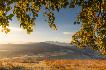 Wall Mural - A beautiful autumn landscape of the Tatra Mountains seen from Polish Podhale during the golden hour. The sky is painted in warm hues, with the mountains bathed in golden light.