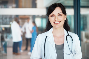 Poster - Portrait, happy woman and proud doctor in clinic for healthcare services, career and medicine. Face, medical professional and confident physician with smile at wellness hospital ready for nursing