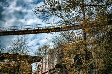 Wall Mural - Swing-a-long suspension bridge above canyon in Chattanooga, Tennessee with beautiful foliage and cloud filled blue sky in background, rope bridge