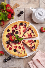 Wall Mural - Tart with cherries strawberries and custard milk cream filling. Open cheesecake pie. Delicious homemade summer dessert with berries. Top view.