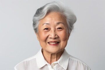 Wall Mural - Portrait of a grinning asian elderly woman in her 90s donning a classy polo shirt in front of white background
