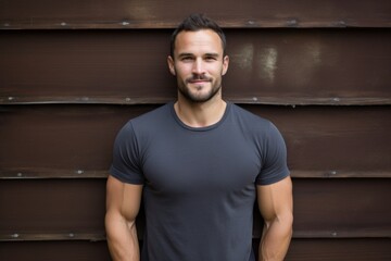 portrait of a content man in his 30s dressed in a casual t-shirt isolated in rustic wooden wall