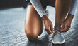 © peopleimages.com - Gym, hands and person tying shoes to start exercise, training or workout at health club on floor. Legs, athlete and tie lace on sneakers to prepare or getting ready for sport, fitness or wellness
