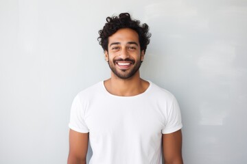Wall Mural - Portrait of a grinning indian man in his 30s donning a trendy cropped top while standing against modern minimalist interior