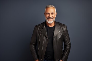 Wall Mural - Portrait of a happy man in his 50s sporting a classic leather jacket while standing against modern minimalist interior