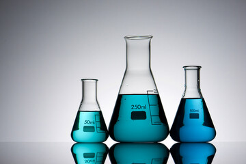 Sticker - Three glass flask placed in a laboratory table with blue liquid