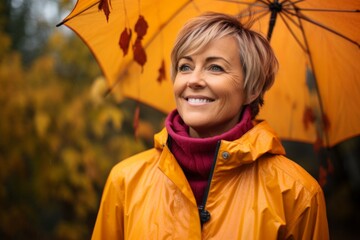 Wall Mural - Portrait of a satisfied woman in her 50s wearing a vibrant raincoat isolated on background of autumn leaves