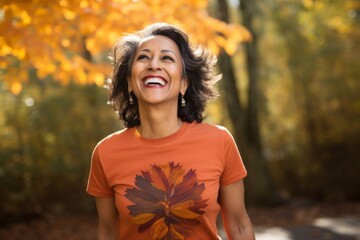 Sticker - Portrait of a cheerful indian woman in her 50s sporting a vintage band t-shirt over background of autumn leaves