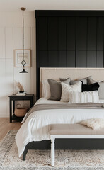 Wall Mural - A black and white bedroom with a large bed, plush pillows on the headboard, an elegant bench at one end of it, and small side tables on either side. The walls have light beige wallpaper.