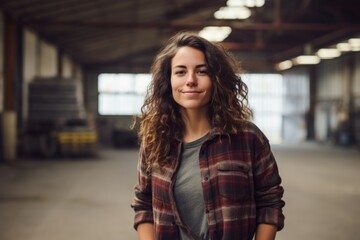 Wall Mural - Portrait of a grinning woman in her 30s dressed in a relaxed flannel shirt while standing against bustling factory floor