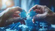 © apirom - Close-up of hands connecting puzzle pieces with business terms on a blue background, representing strategic planning