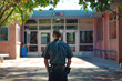 © karina_lo - Armed security guard keeps order in college or school, police officer stands at university. Concept of uniform, secure, service, safety