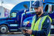 © pham - A truck driver uses a tablet computer while standing in front of a semi-trailer truck at a loading dock
