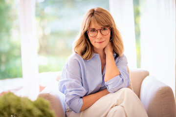 Mid aged woman relaxing in an armchair in her modern home