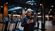 © Iryna - Senior woman using smartphone in gym