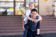 © Ольга Апанасенко - Two schoolchildren are standing on the porch of the school. One boy climbed on the back of another boy. They're playing, having fun. Back to school