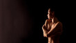 © Prostock-studio - This image shows a woman standing in a dark room with her arms crossed over her chest. The lighting is soft and highlights her body and face in silhouette.