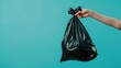 © Mamstock - Woman s hand discarding black plastic waste bag on soft colored background with space for text