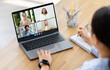 © Prostock-studio - A woman trainee sits at a desk with a laptop open, participating in a video conference meeting. The screen displays four people, each in a separate video tile.