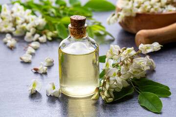 Wall Mural - Robinia (false acacia) essential oil (remedy, extract) bottle with fresh acacia flowers