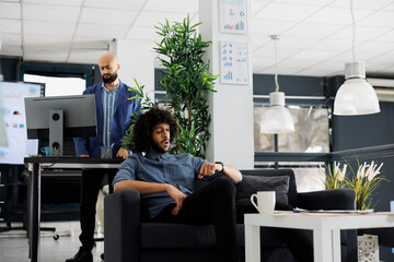 Poster - Shocked arab businessman checking time on watch and waiting for business meeting while sitting on couch in coworking space. Start up company executive manager looking at wristwatch in office
