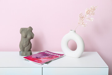 Poster - Vase with dried twig, figurine and magazines on dresser near pink wall