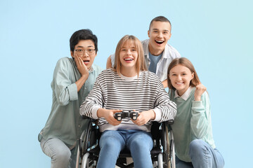 Wall Mural - Group of teenagers with girl in wheelchair playing video game on blue background