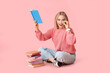 © Pixel-Shot - Beautiful young happy woman with many books sitting on pink background